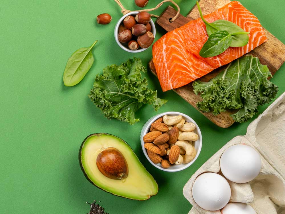 Auswahl nährstoffreicher Lebensmittel wie Lachs, Avocado, Nüsse, Eier und Blattgemüse als Beispiel für eine gesunde Ernährungsberatung